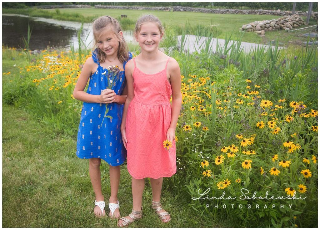 two sisters in summer dresses holding flowers