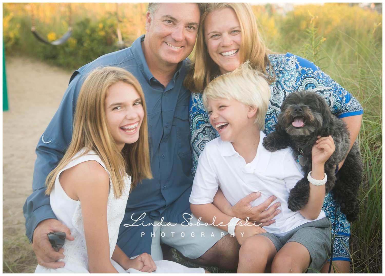 beautiful family of four at the beach with their dog