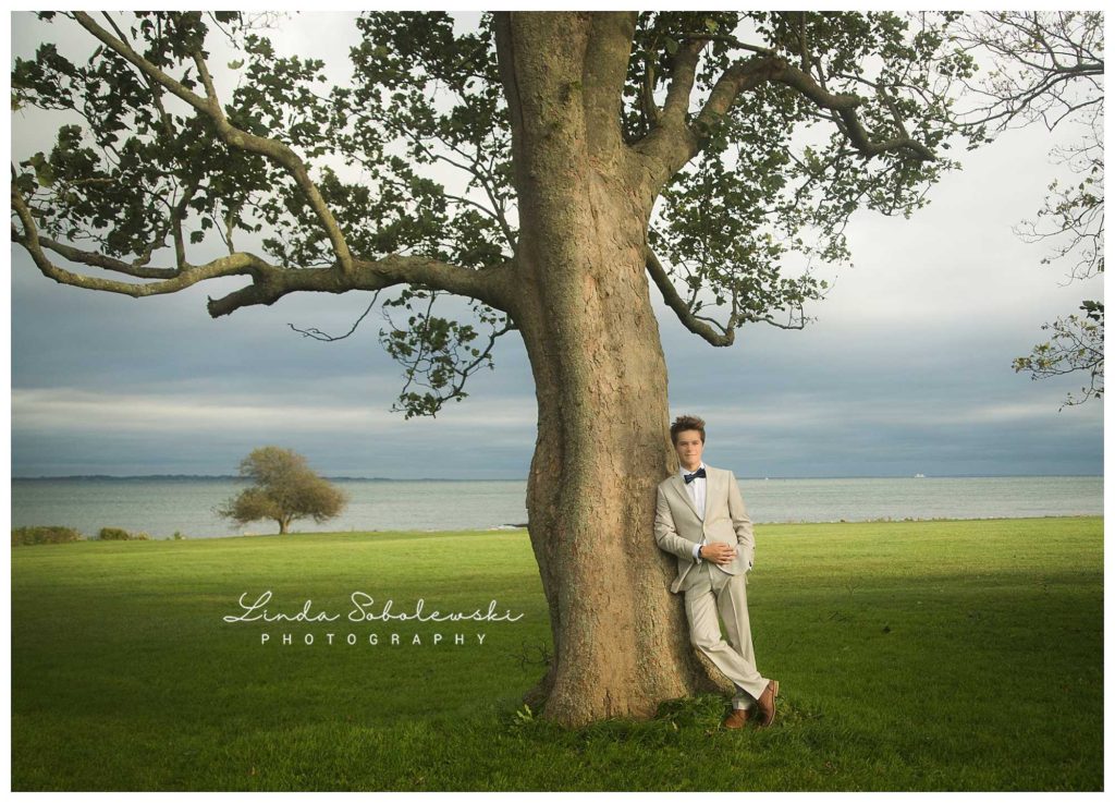 senior boy leaning against a large tree