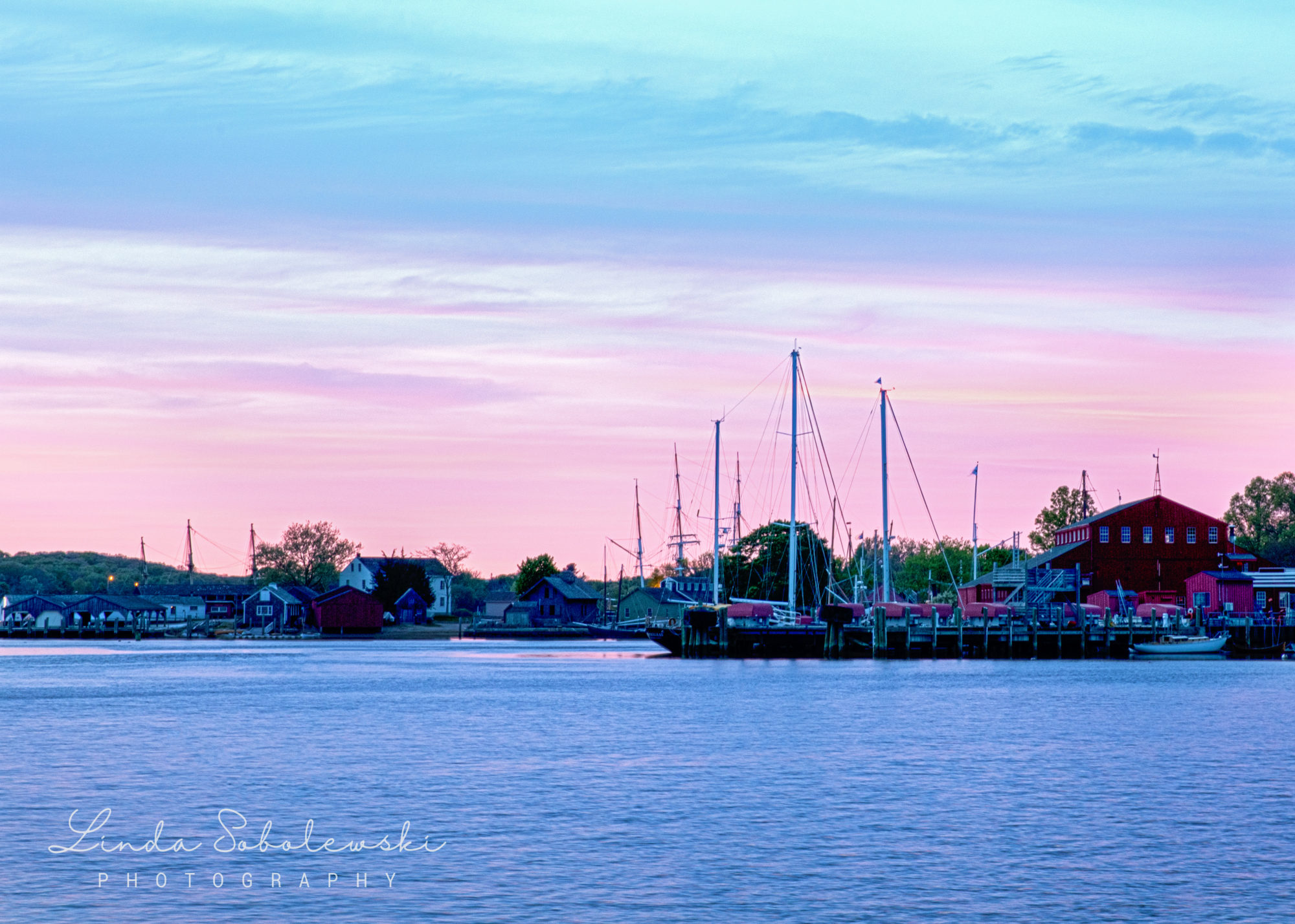 pink and blue skies with a boat in downtown essex, ct