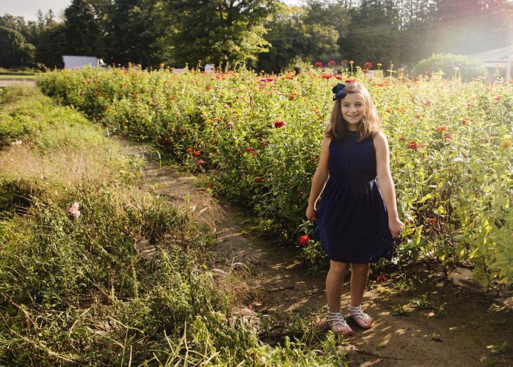 girl in blue dress standing in field of flowers