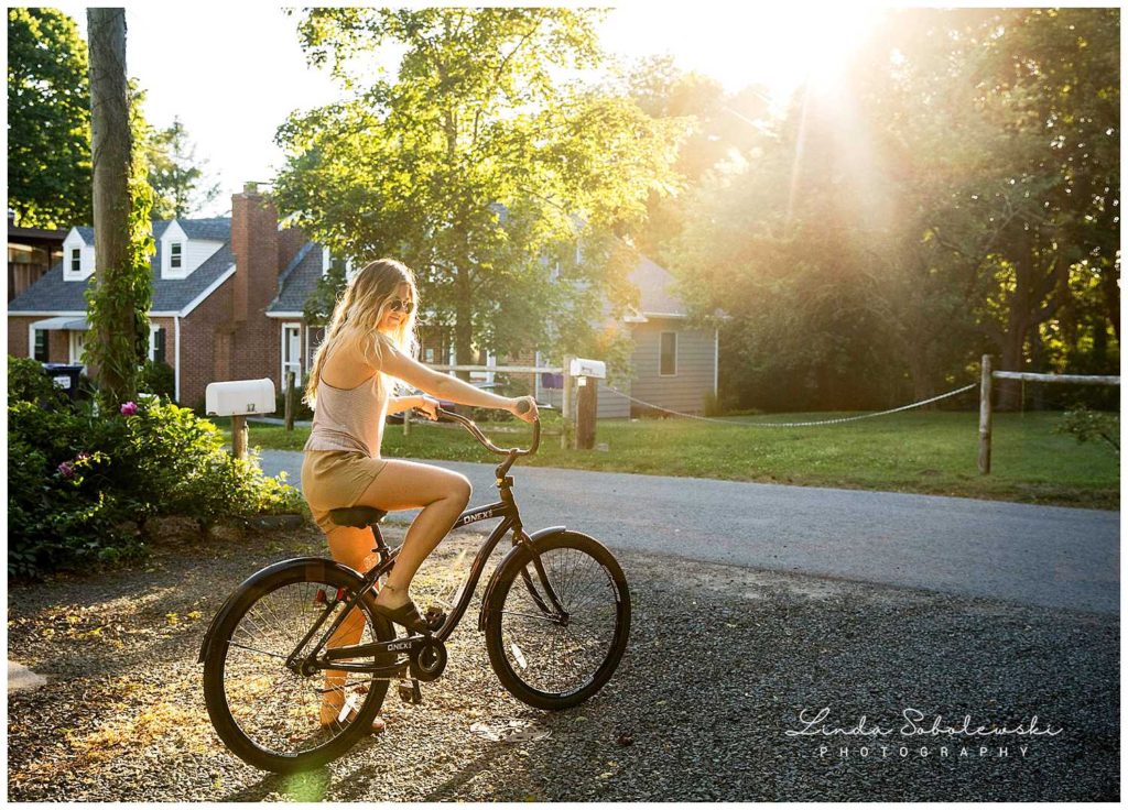 girl with long blonde hair on a bike with the sun shining down, westbrook ct photographer