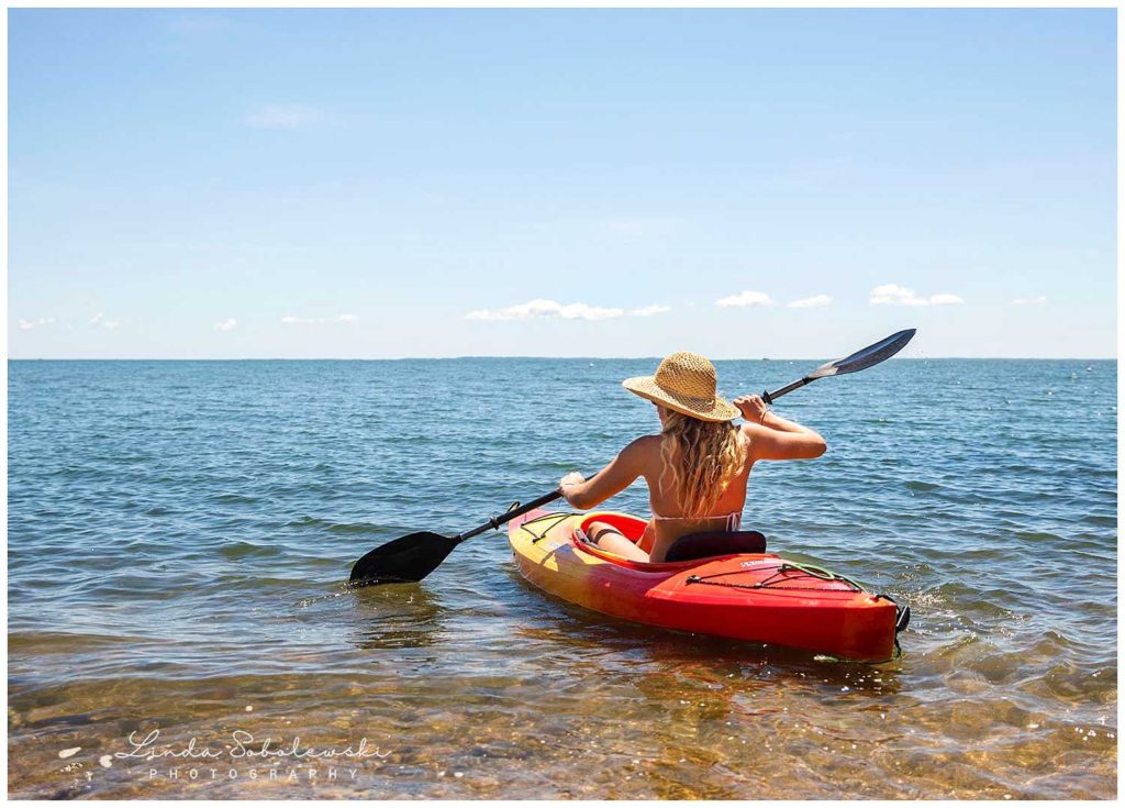 girl with hat paddling in a kayak, connecticut photographer