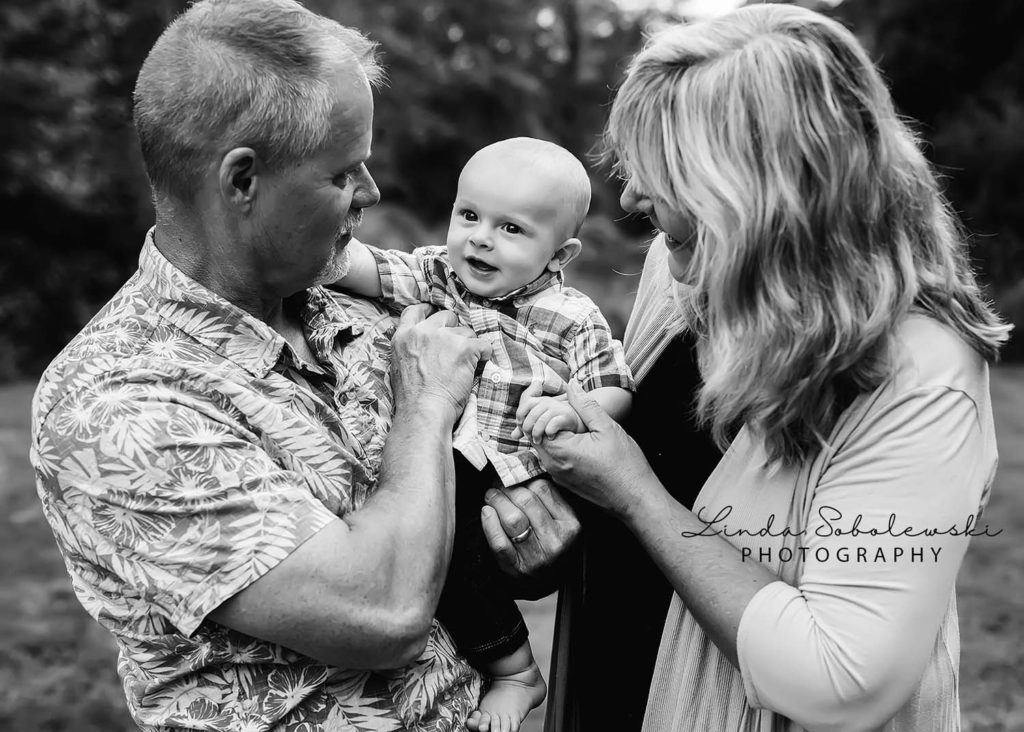 grandparents holding laughing baby boy