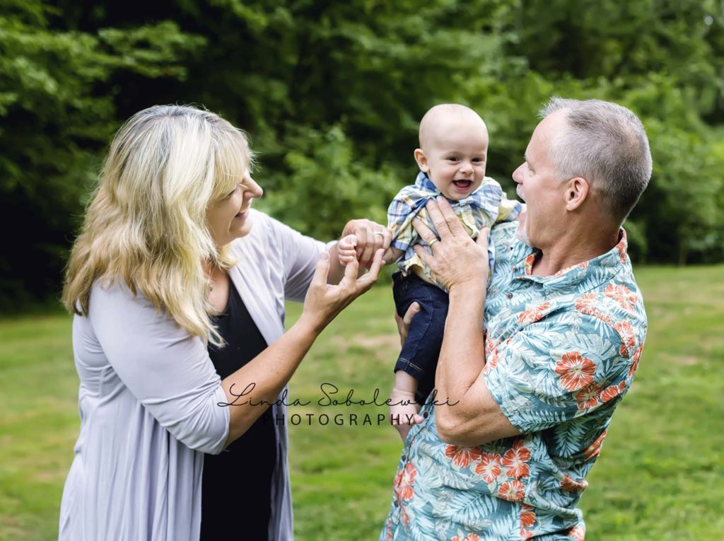 grandparents holding laughing baby boy