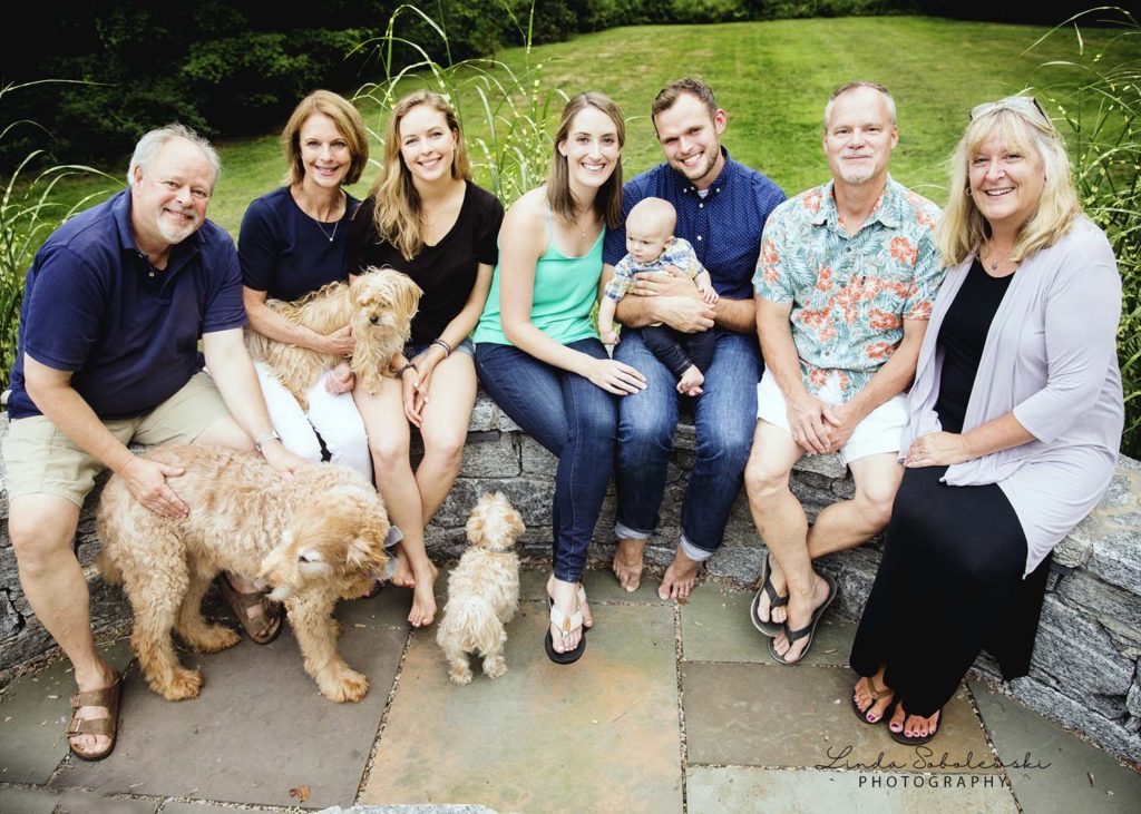 baby boy surrounded by loving grandparents and parents and dogs
