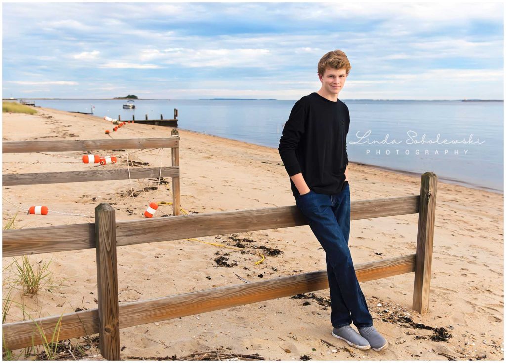 senior boy in black shirt leaning against fence