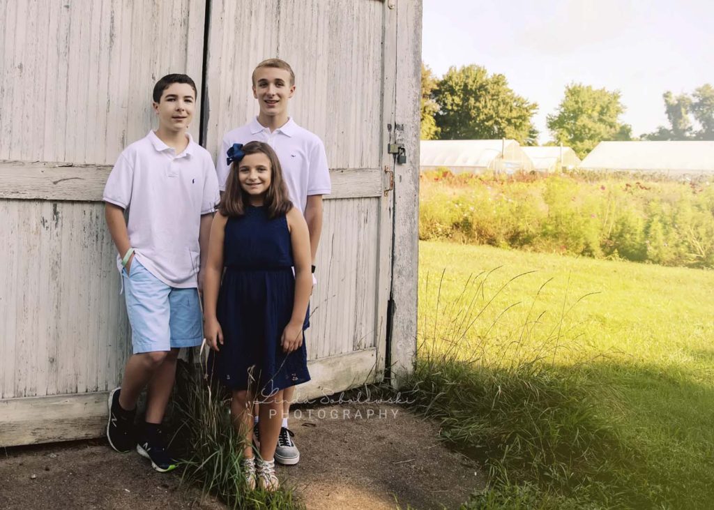 siblings in front of white shed