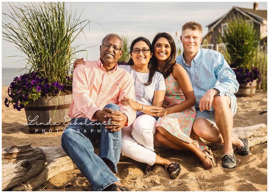 adult couple and her parents sitting on log on the beach, Father's Day session