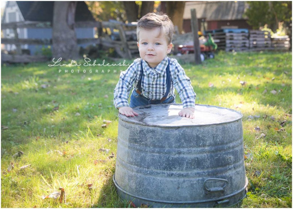 baby boy smiling with hands on metal bucket
