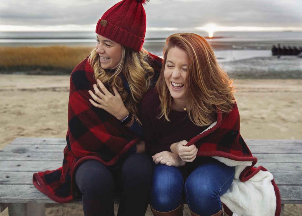 two girls laughing with a blanket wrapped around them at the beach, old Saybrook ct lifestyle photographer