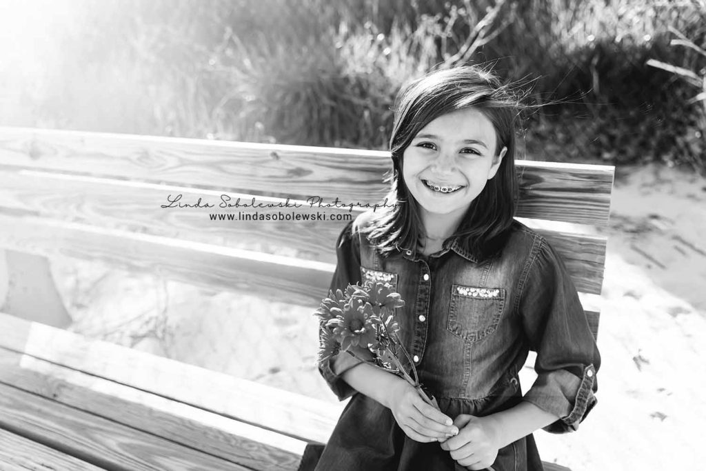 girl with braces holding flowers, sitting on a bench the beach, Westbrook family photographer
