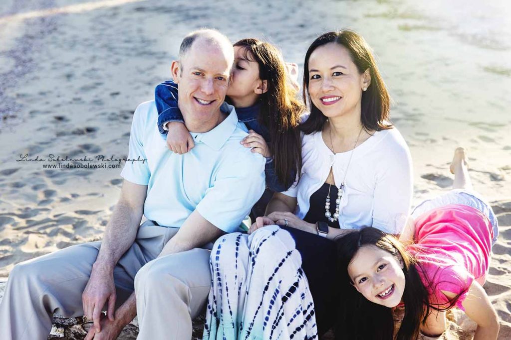 family of four sitting on the beach for a family session, westbrook family photographer