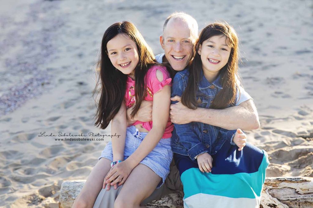 father hugging his two little girls at the beach, Connecticut shoreline family photographer