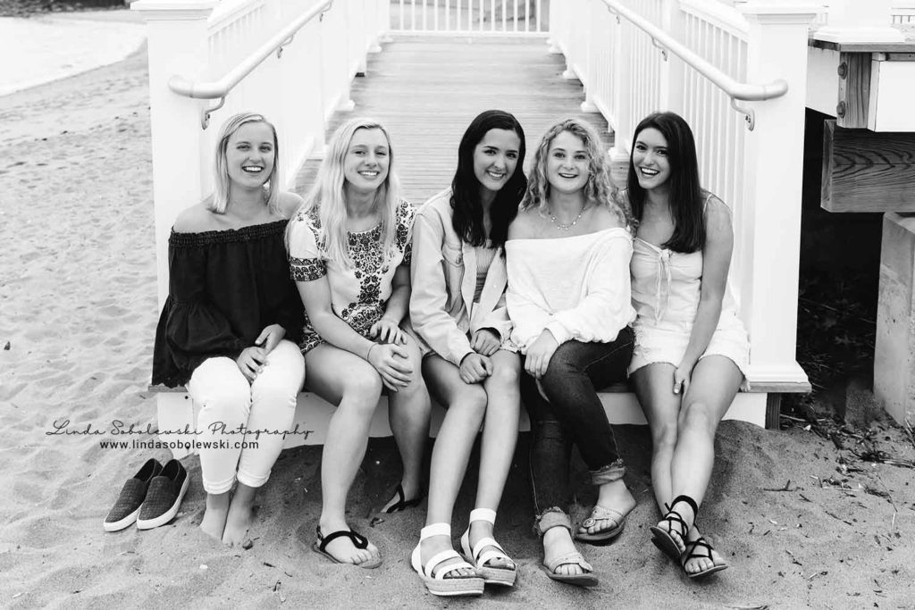 black and white image of five senior girls sitting on the steps at the Madison surf club, Connecticut senior photographer