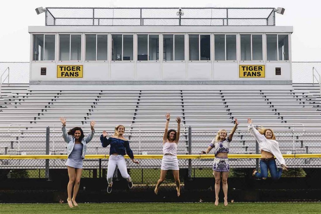 five senior girls jumping in the air on a football field, Madison ct senior photography