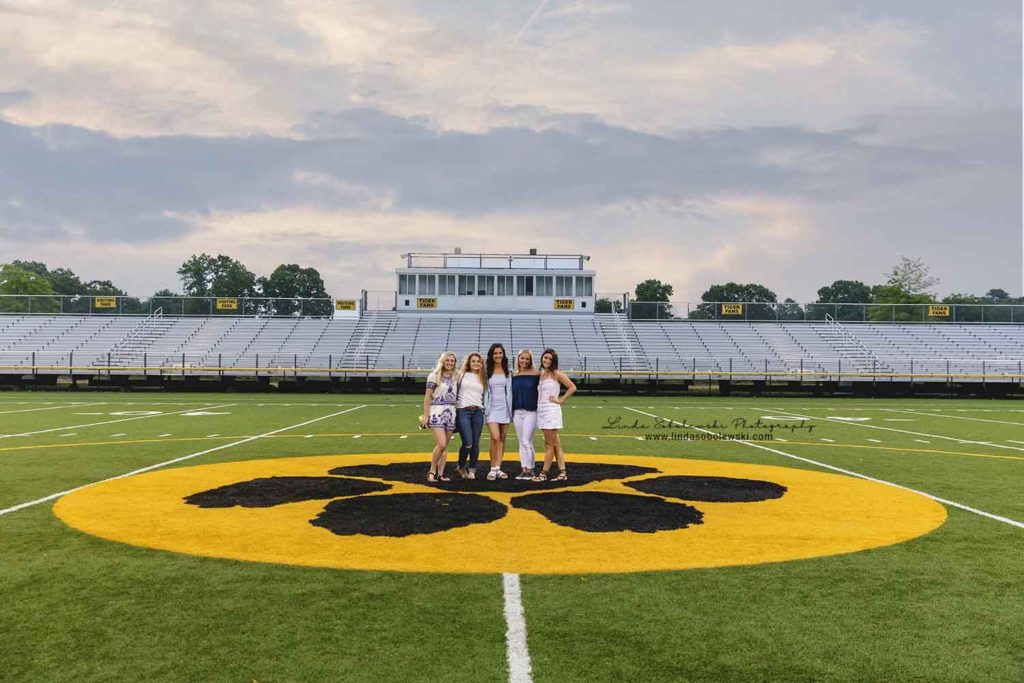five senior girls standing in the middle of the football field, Madison ct senior photographer