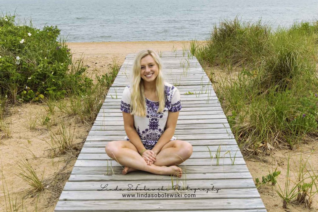 blonde girl sitting on a wooden pier at the beach, Madison ct photographer