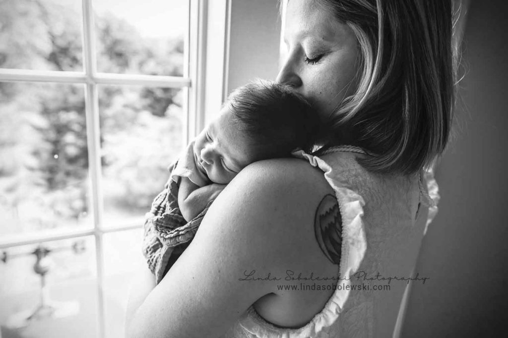 black and white image of mom holding her new baby boy, guilford new family of four photo session