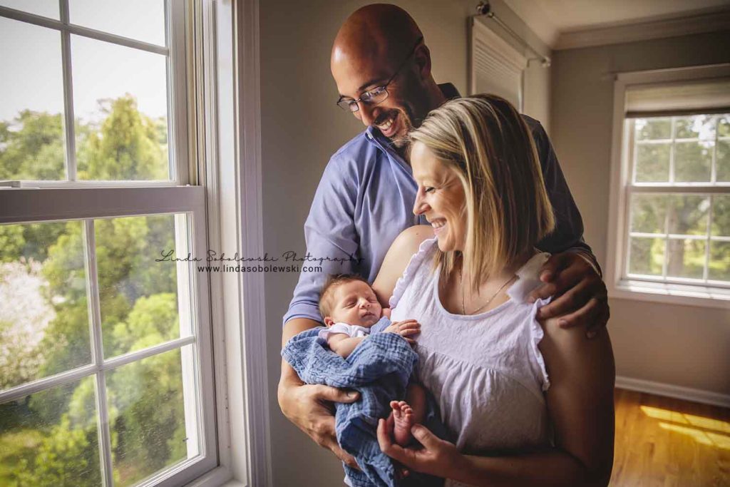 mom and dad smiling at their new baby son, guilford new family of four photo session