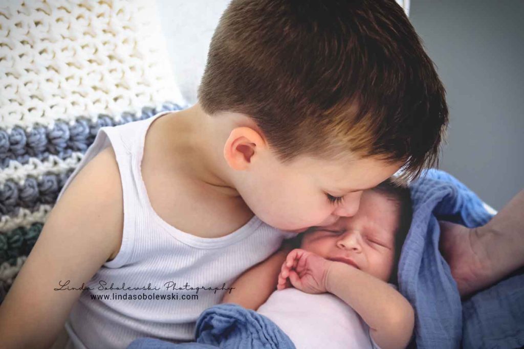 big brother kissing his newborn baby brother, guilford new family of four photography session