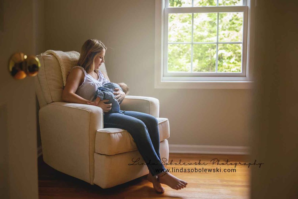 mom holding her newborn baby boy in a chair, guilford ct family photographer