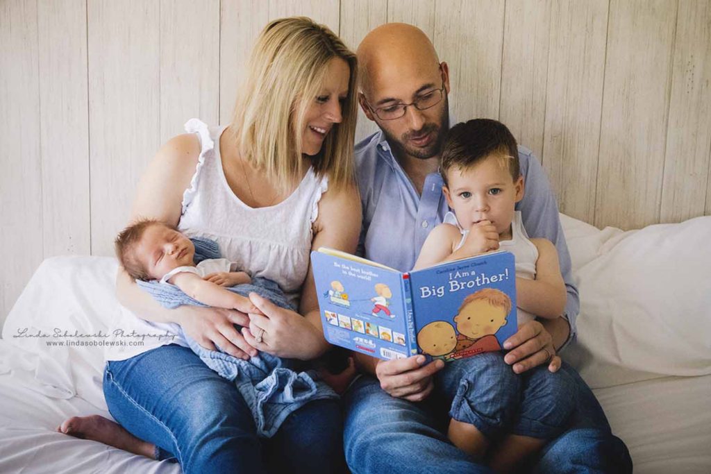 family of four reading a book in bed, guilford newborn photographer