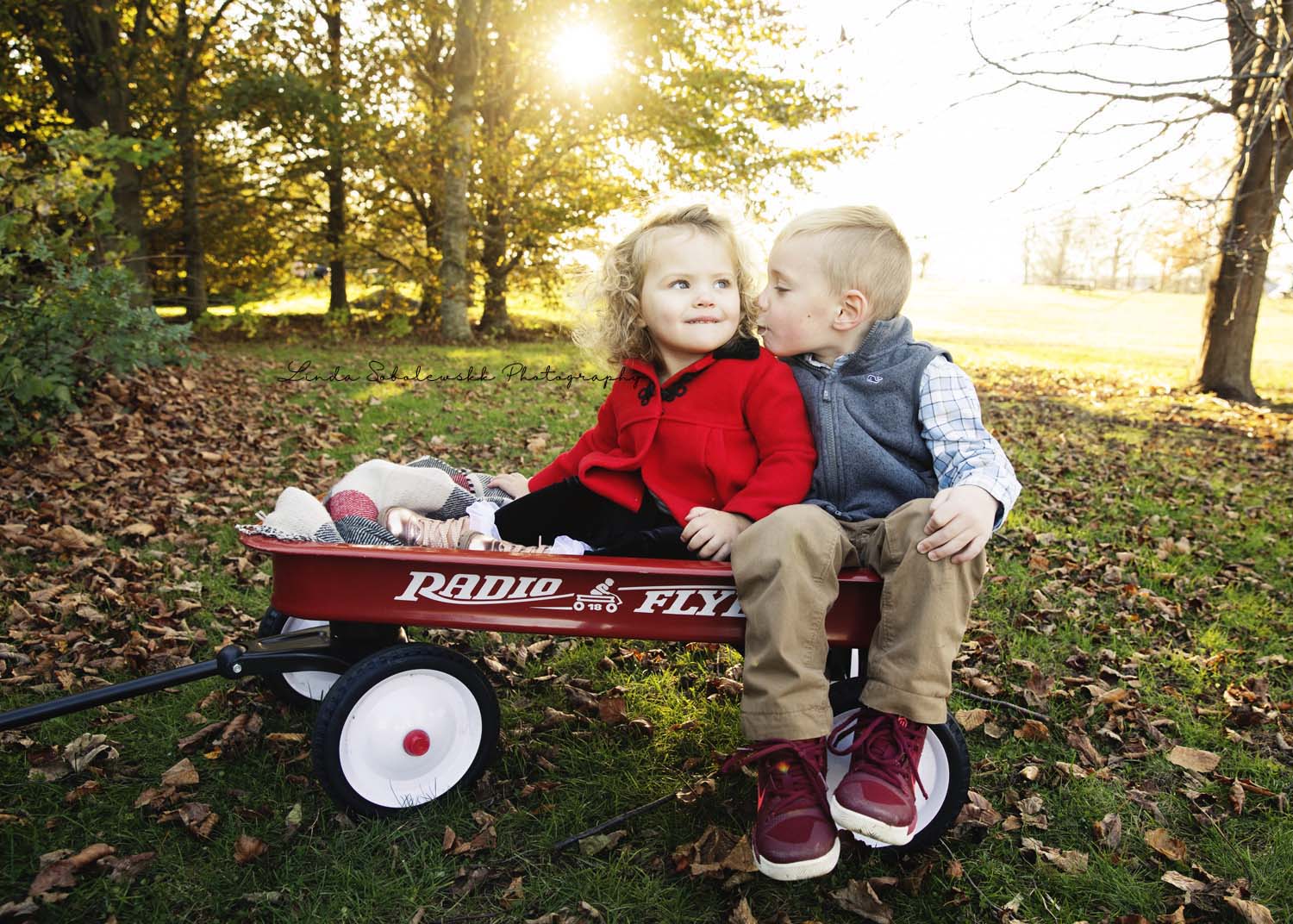 little boy kissing his sister in a red wagon, harness memorial family session
