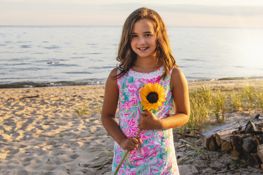 girl in pink dress holding a sunflower at the beach, connecticut famiily photographer