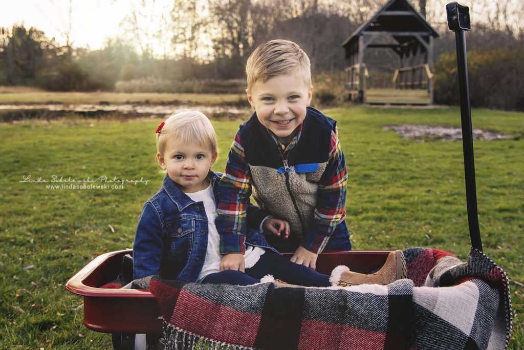 brother and sister in a red wagon at Bauer Park in Madison, CT photography session