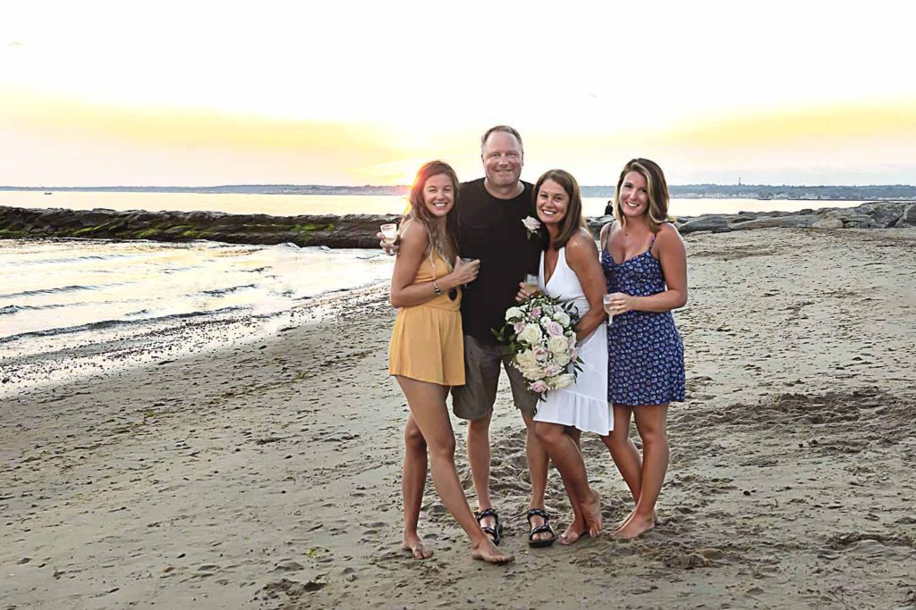 family of four standing on the beach at sunset, 30th anniversary celebration