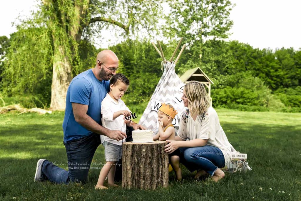 little boy and his familyeating his cake at his one year old photo session, Connecticut Best Family Photographer
