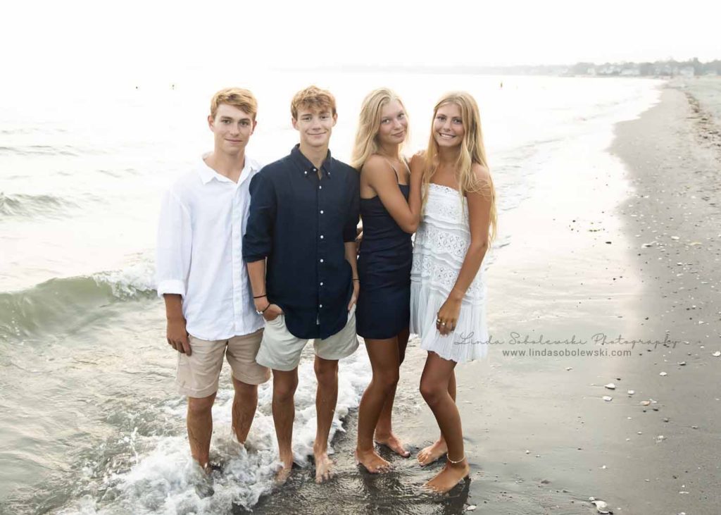 our siblings standing in the water at the beach for a family beach photoshoot