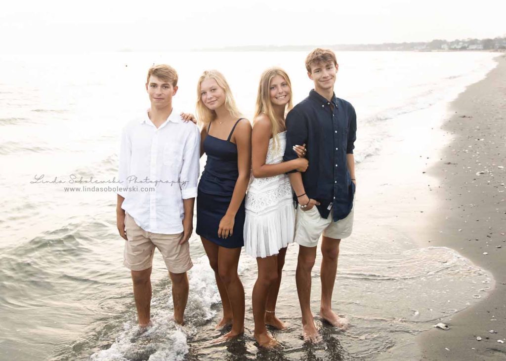 our siblings standing in the water at the beach for a family beach photoshoot