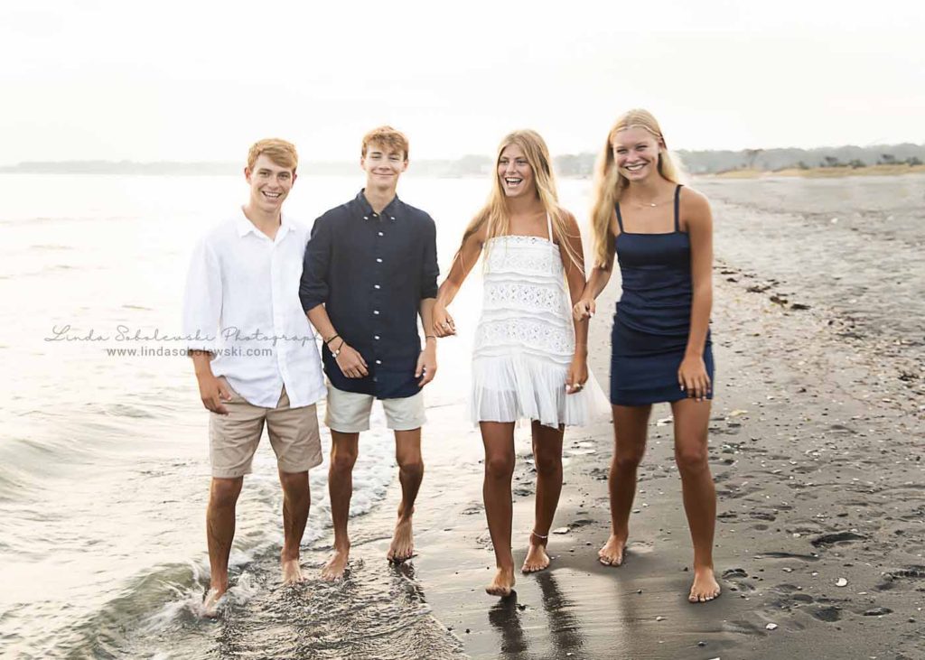 four siblings standing in the water at the beach for a family beach photoshoot