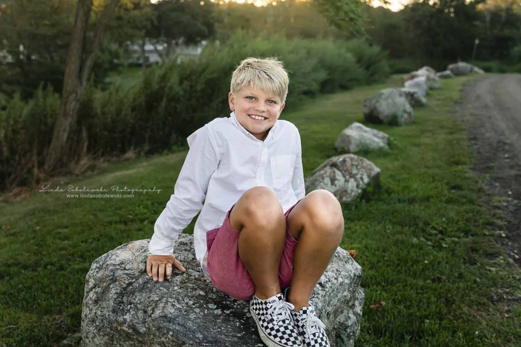 boy in white shirt sitting on a rock, CT shoreline family photographer