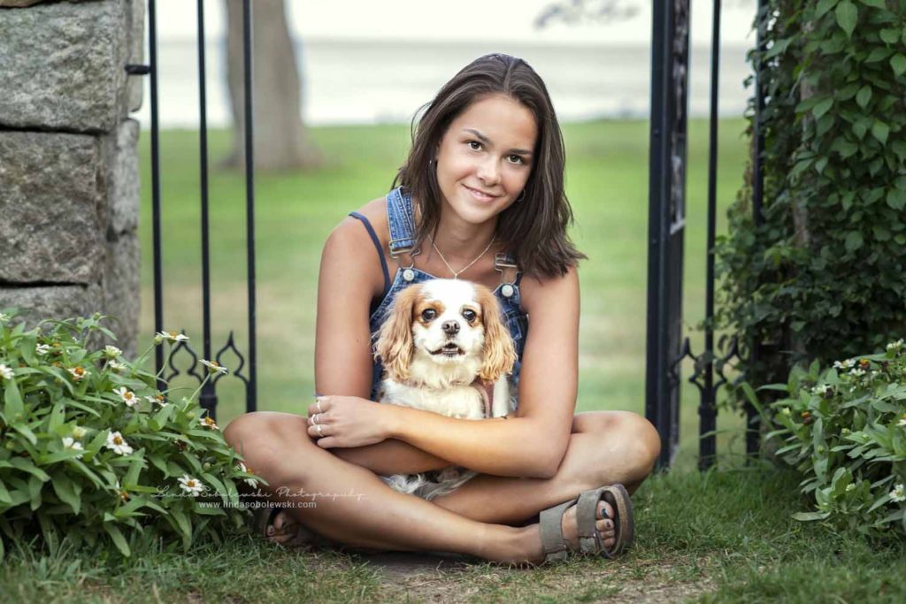 girl in denim overalls holding her dog, CT shoreline senior and family photographer