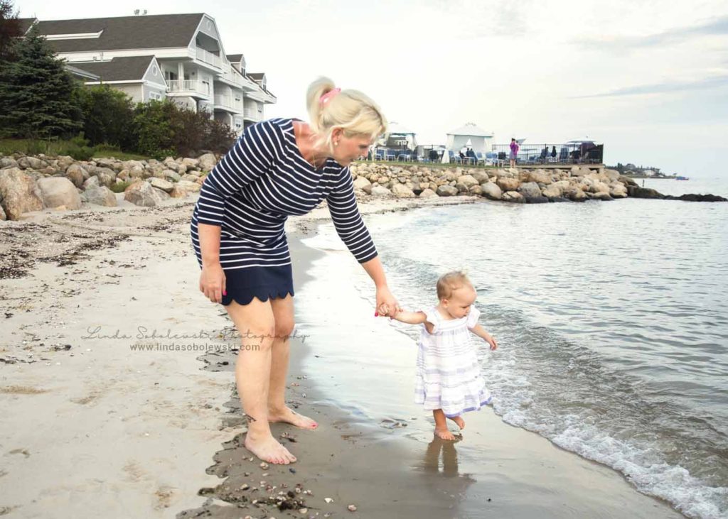 mom holding her baby's hand at the beach, Family Photoshoot at Water's Edge