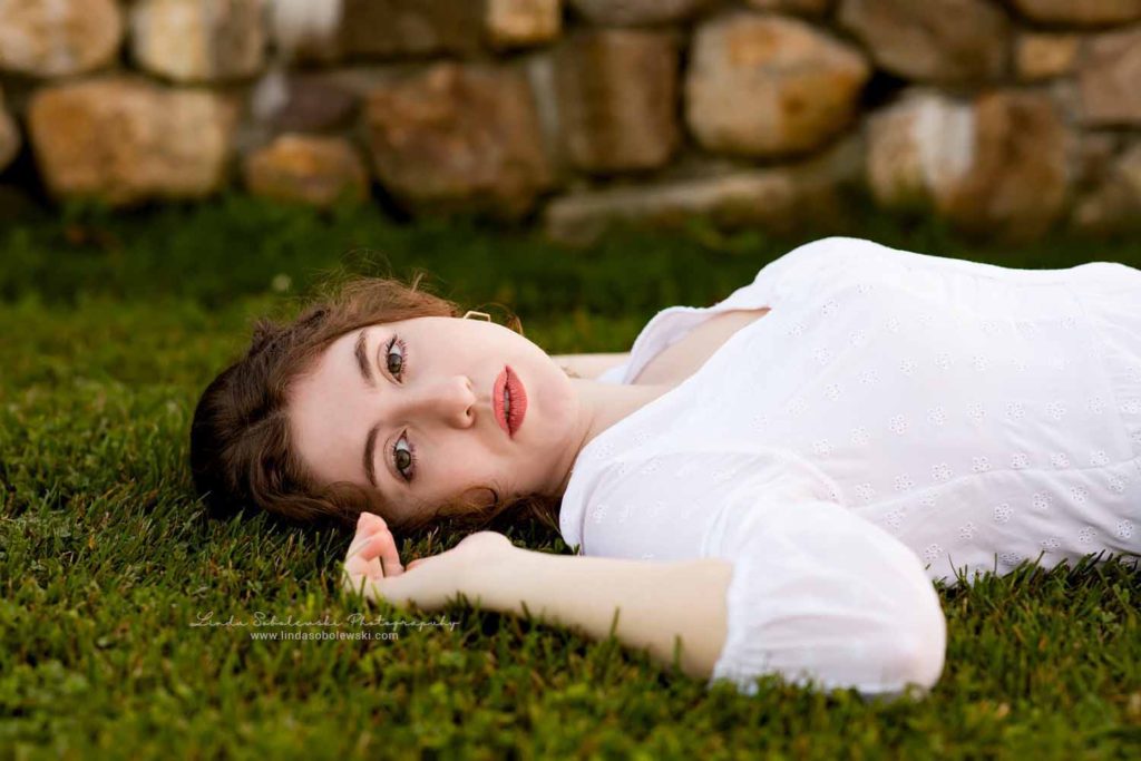 girl in white dress laying in the grass CT's best family and high school senior photographer