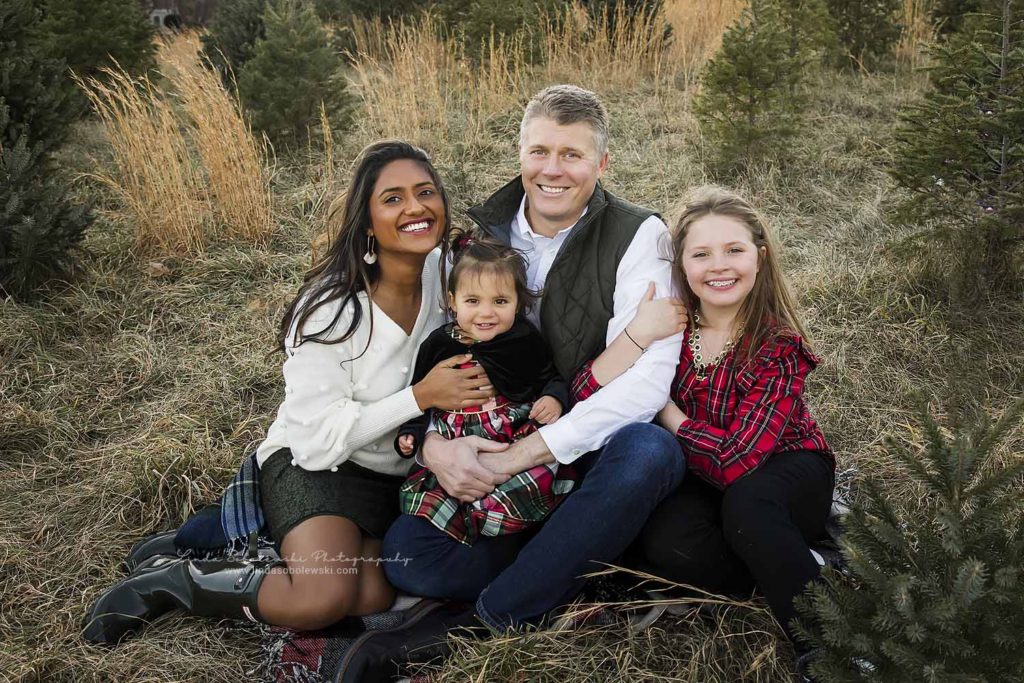 family of four sitting in a field for their Christmas Tree Farm Mini Session, Old Saybrook Family Photographer