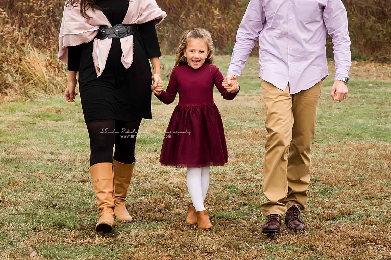 mom and dad holding hands with their little girl, Madison, CT fall family photo session