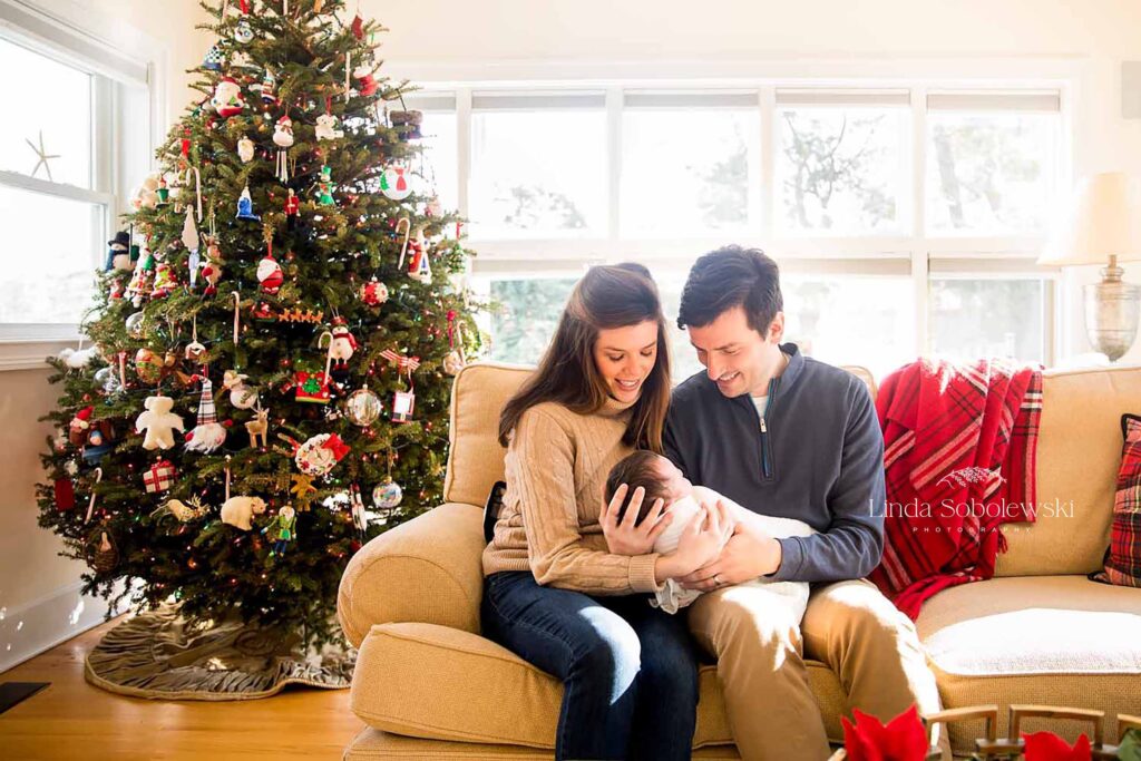 parents holding their new baby by their christmas tree, old saybrook newborn photographer
