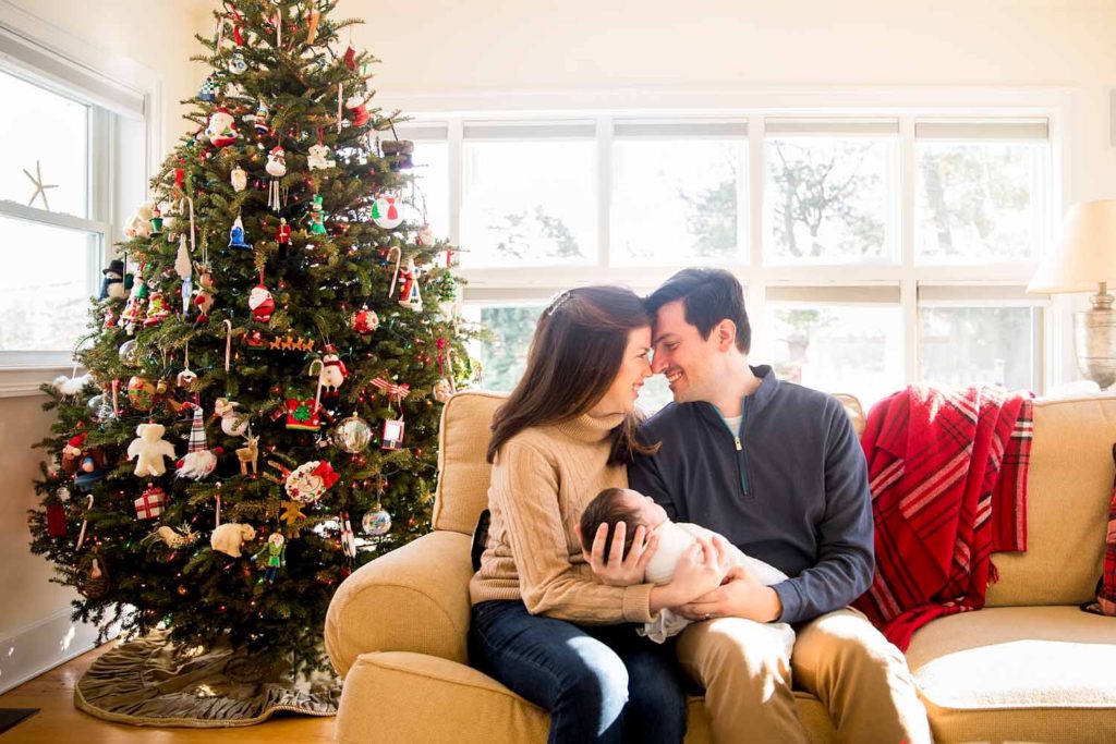 mom and dad holding their new baby girl in front of the Christmas Tree, CT shoreline photographer