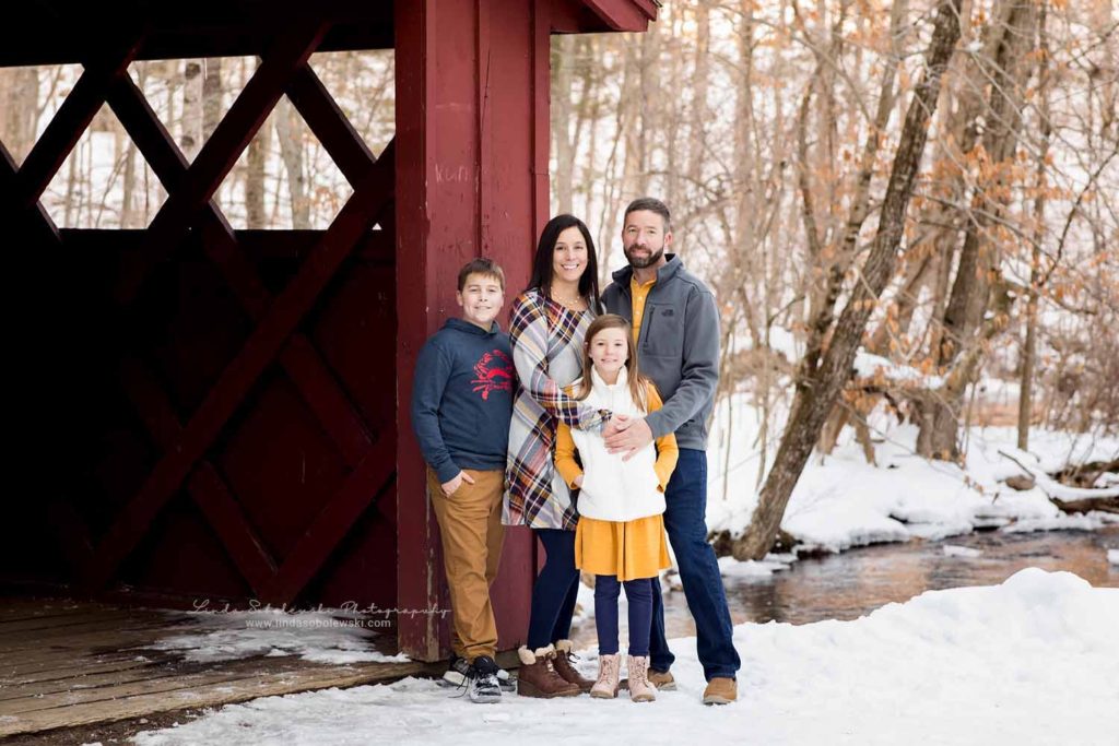 mom, dad and two children at a covered red bridge, CT Family photographer