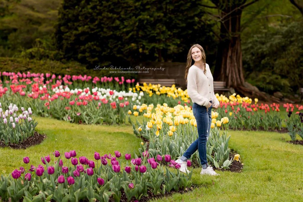 teenage girl in jeans standing in a tulip garden, Senior photo session at Elizabeth State Park, West Hartford, CT Photographer