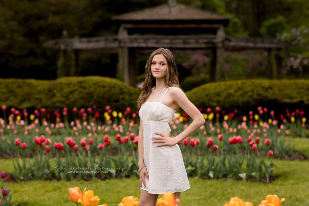 teenage girl in white dress standing in a tulip garden, Senior photo session at Elizabeth State Park, Old Saybrook CT Photographer