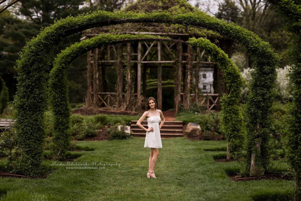girl in white dress standing under an archway, Senior Photos at the Park, CT Senior Photographer