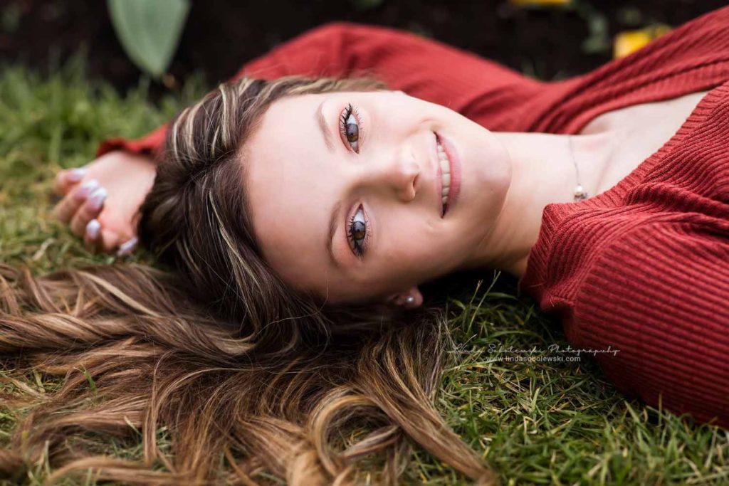 girl in red sweater laying on the ground, Senior Photo Session with West Hartford, CT Senior photographer