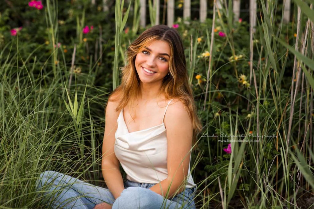 teenage girl sitting in front of fence, Beautiful Senior Photos in Madison, CT