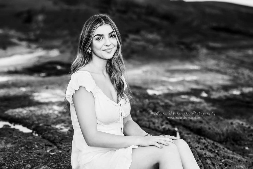 black and white image of a high school senior sitting on a rock. Guilford, CT photographer